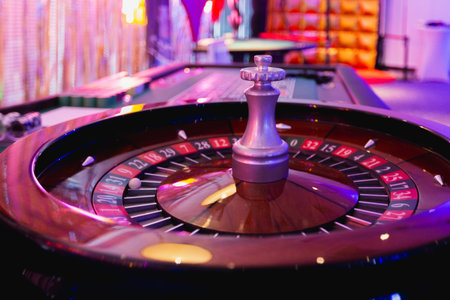 Roulette table in casino with red and black roulette wheel.