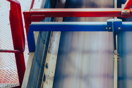 Motion blur conveyor belt inside an industrial recycling facility. Automated transport system with metal barriers and processing equipment used for waste sorting, material handling, and recovery operations in a factory environment.