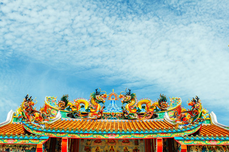 Dragon statue, decorated on the roof of a Buddhist temple in Thailand. Blue sky background with light cloudsの写真素材