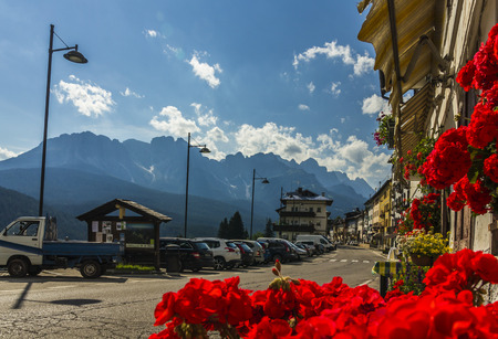 Road in alpine village with red flowers on house balconyの写真素材