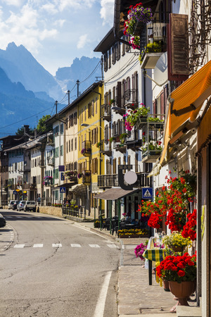 Road in alpine village with red flowers on house balconyの写真素材