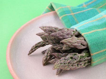 plate of fresh green asparagus on green background - close-upsの写真素材