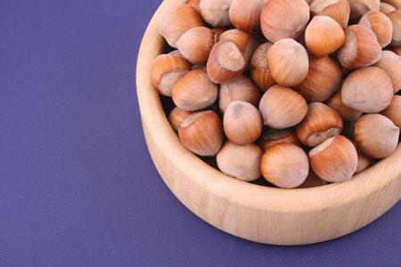 wooden bowl full of hazelnuts isolated on blueの写真素材