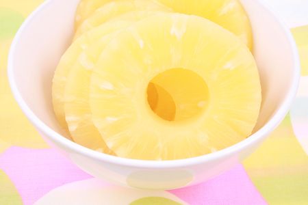 bowl full of sliced pineapple on colorful backgroundの写真素材