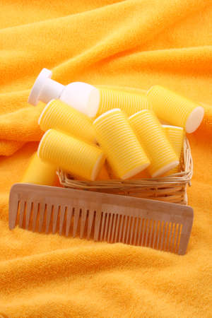 hair care - curlers shampoo and comb on yellow towelの写真素材