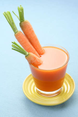 glass of fresh carrot juice and some fresh vegetablesの写真素材