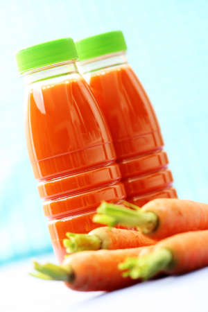 two bottles of carrot juice and some fresh carrotsの写真素材