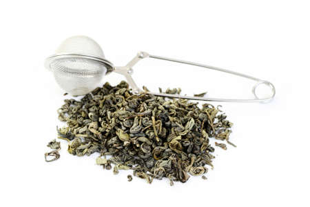 pile of green tea and tea infuser isolated on whiteの写真素材