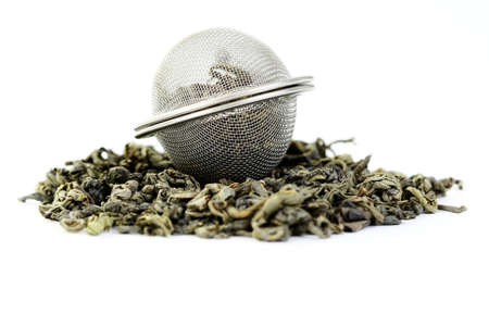 pile of green tea and tea infuser isolated on whiteの写真素材