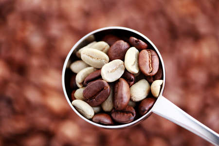 spoon of coffee beans on coffee background - coffee timeの写真素材