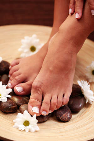 female feet with pebbles and flowers - beauty treatmentの写真素材