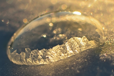 Frozen soap bubble. Cold winter liquid ball experiment. Freezing water with icy patter textureの写真素材