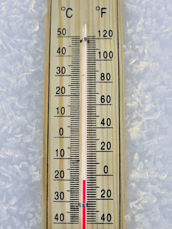 Mercury wooden thermometer stuck on snow in forest shows very low temperatures. Temperatures in...