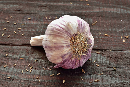 Garlic cloves and garlic bulb on vintage wooden table. Spicy cooking ingredient. Natural herbal medicine vegetable.の写真素材