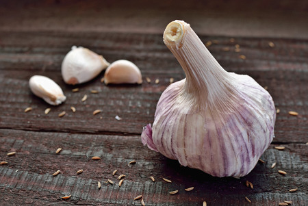 Garlic cloves and garlic bulb on vintage wooden table. Spicy cooking ingredient. Natural herbal medicine vegetable.の写真素材