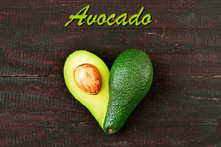 Fresh avocado in the shape of a heart isolated on wood table background. Love symbol made of fruit. Exotic fruit.の写真素材