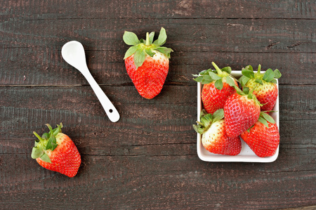 Strawberry fruit on wood background. Forest fruit in white idaeus and spoon. Delicious fresh berries.の写真素材