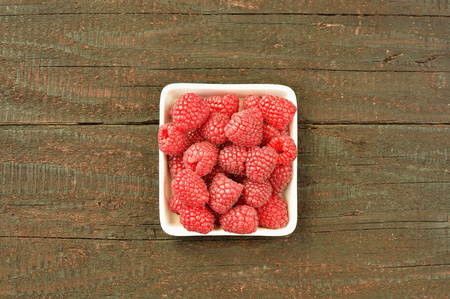 Raspberry fruit on wood background. Forest fruit in white idaeus. Delicious fresh berries.