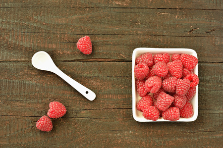 Raspberry fruit on wood background. Forest fruit in white idaeus and spoon. Delicious fresh berries.