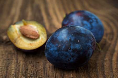 Fresh blue plums  on wood table background. Sweet autumn fruit. Delicious and healthy raw food full of vitamins.の写真素材