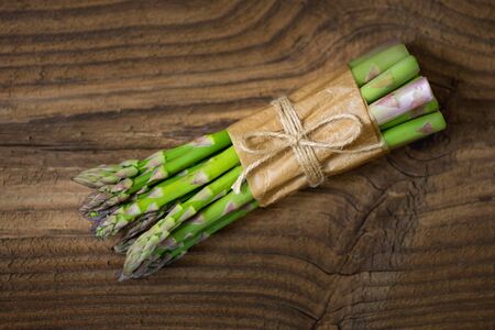 Bunch of raw asparagus on wooden table. Green fresh harvested vegetable. Healthy meal. Vegetarian and vegan food.の写真素材