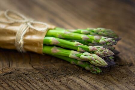 Bunch of raw asparagus on wooden table. Green fresh harvested vegetable. Healthy meal. Vegetarian and vegan food.の写真素材