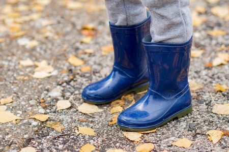 Feet of child in blue rubber boots jumping over a puddle after the rain. Close up of child wellies in autumn weatherの写真素材