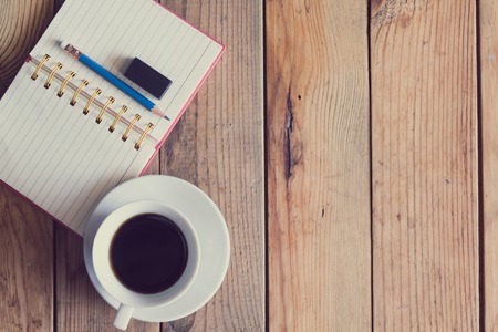 cup of coffee and  pen on old wooden table