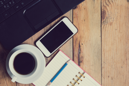 Laptop (notebook) with cup of coffee and  pen on old wooden tableの写真素材