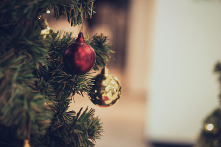 bauble hanging from a decorated Christmas tree. Retro filter effect