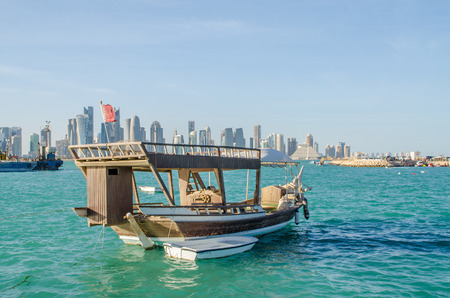 Dhows moored off Museum Park in central Doha, Qatar, Arabia, with some of the buildings from the city\'s commercial port in the background.のeditorial素材