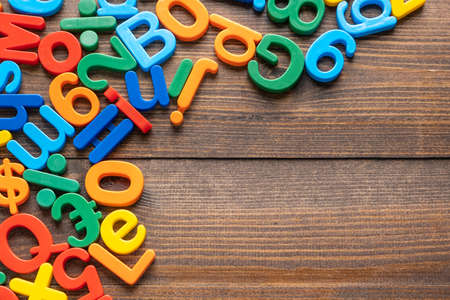 Top view of colorful plastic letters and numbers on wooden background