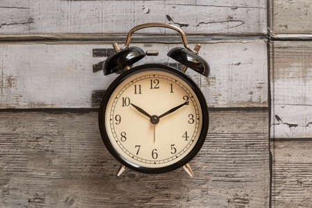 Black retro alarm clock on wooden background