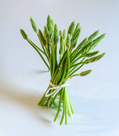 tied bouquet of fresh wild asparagus on a white background standing upの写真素材