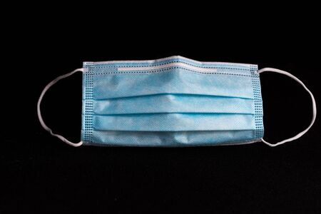 close-up of a blue surgical mask isolated on black background