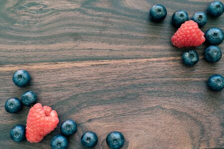 panoramic close-up of raspberries and blueberries on wooden background. top view and copy space for textの写真素材