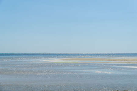 Minimalist seascape with blue ocean and sandbank on a sunny day. Sky is clear blue