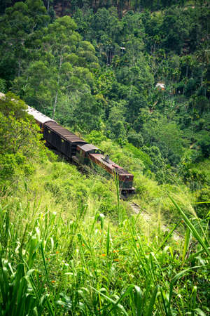 Green and red train on the famous nine arches Bridge in highlands near Ella, Sri Lanka. Jungle and...
