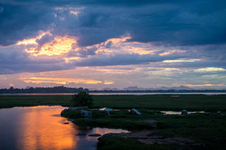 Storm clouds over the water with the sunset over the lake, orange sunlight, dramatic sky with clouds. Beautiful reflections in waterの写真素材