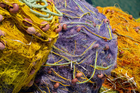 Colored purple and yellow fishing nets with orange floats. Bright multi-colored backdrop. Hobby fishing concept. Selective focus. Copy space.の写真素材