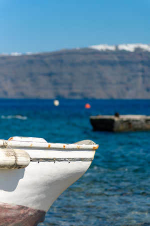 Colorful greek fishing boat on Santorini island, Greece. Thira vllage in the backgroundの写真素材