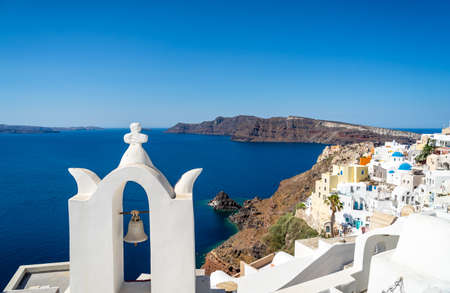 Panoramic view of Santorini caldera with Oia town and famous old white tower bells and blue domes of...
