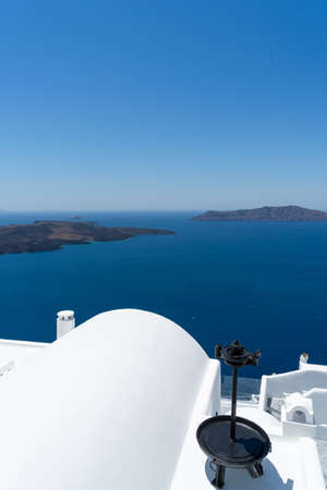 Old metallic tool for decoration on a white roof of a house of Santorini island, Greece. Blue Mediterranean sea and Santorini caldera in the background. Portrait formatの写真素材