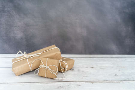 Christmas and zero waste, eco friendly packaging. wrapped gifts in craft paper on a wooden table on a dark background. ecological Christmas holiday concept, eco decorの写真素材