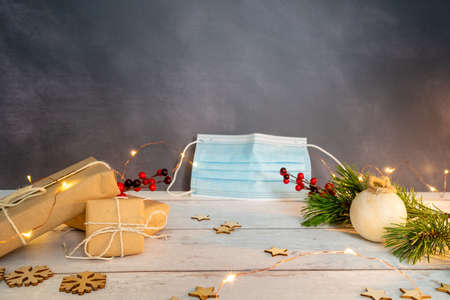 Christmas and zero waste, eco friendly packaging. wrapped gifts in craft paper and Christmas decoration on a wooden table. Blue surgical mask on gray background. ecological Christmas holiday concept, eco decorの写真素材