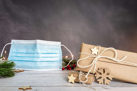 Christmas and zero waste, eco friendly packaging. wrapped gifts in craft paper and Christmas decoration on a wooden table. Blue surgical mask on gray background. ecological Christmas holiday concept, eco decorの写真素材