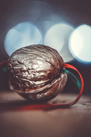 close-up of a painted silver nut with red and green ribbon on a dark background. christmas...