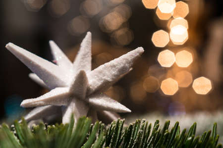 christmas decoration. close-up of a white design snowflake on a christmas tree branch. beautiful blurred and shiny backgroundの写真素材