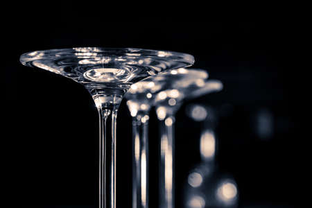 Detail of three glasses standing upside down on a dark background. Black nd white photography
