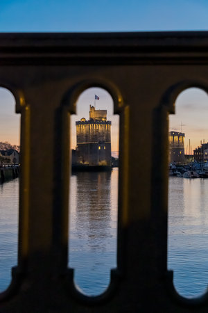 view through balustrade of the old harbor of La Rochelle at blue hour with its famous old towers.のeditorial素材